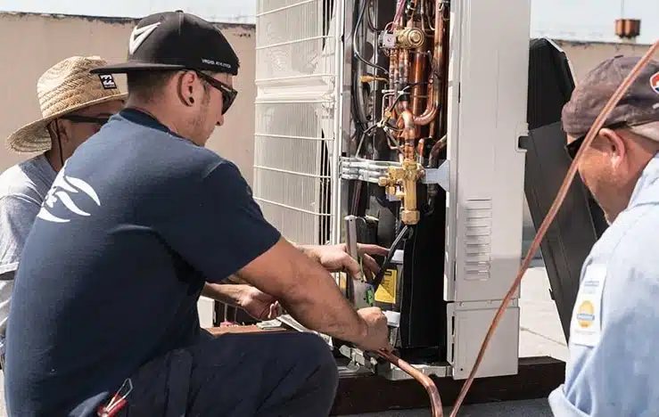 Commercial air conditioning installation technicians working on rooftop HVAC units for a business building
